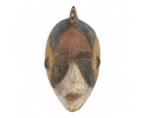 A polychrome painted tribal African mask - in red, white and umber, with a comb headdress, 25cm high.