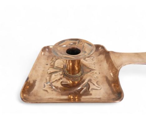 A Newlyn copper chamber stick - with a square pan and circular sconce repousse decorated with fish, 25cm wide