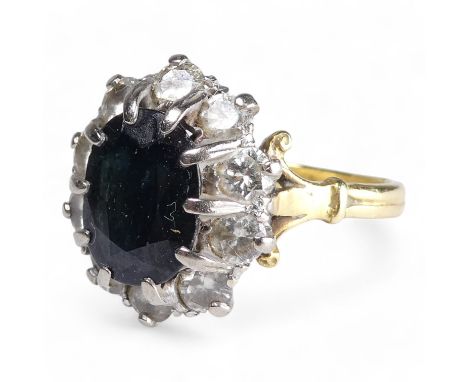 A 9ct sapphire and diamond ring - the claw set oval central stone within a band of diamonds, size R, 6.6g.