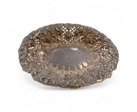 A silver bread plate - London 1892, oval with a pierced grape and foliate repousse design and raised on bracket feet, 304g.