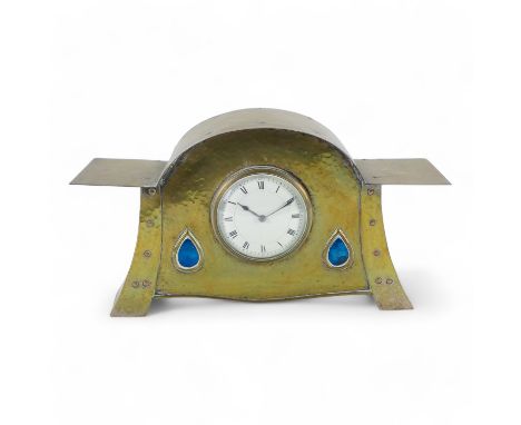 An Arts and Crafts mantel clock in the manner of Liberty &amp; Co. - the planished silvered case with decorative brass rivets