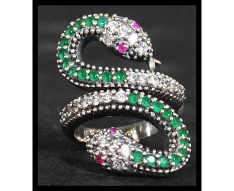 A sterling silver silver CZ and emerald adorned ring in the form of a coiled snake with ruby set eyes. Weighs 11 grams.