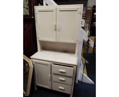 A 1950s white painted kitchen cabinet, the top section with two doors enclosing shelves and the base with three drawers and c