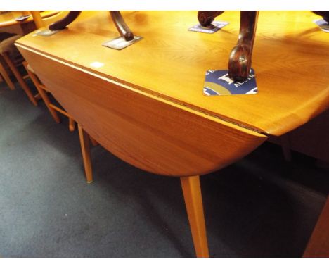 An Ercol light elm circular drop leaf dining table