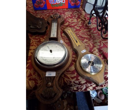 An oak cased aneroid barometer with thermometer above together with another similar