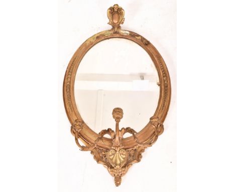 A 19th century George III oval gilt wood and gesso worked girandole mirror. The mirror of rococo influence, the frame of gilt