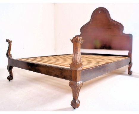 A French Continental early 20th century mahogany double bedstead. The bed framing having a scrolled tall headboard carved wit