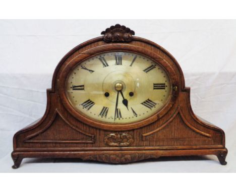 An early 20th Century oak cased mantel clock with large oval dial, applied decoration and Wurttemberg eight day gong striking