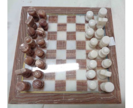 A carved stone and marble chess set and board