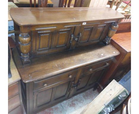 A 1.2m vintage Ercol dark elm court cupboard with pair of panelled cupboard doors to superstructure, over a base with two fri
