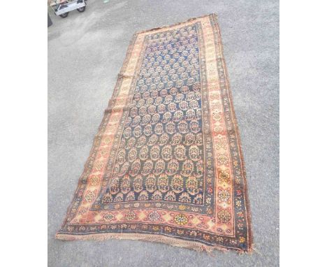 A Middle Eastern handmade wool runner with repeat stylised foliate motifs within a wide border on blue ground - 3m X 1.23m - 