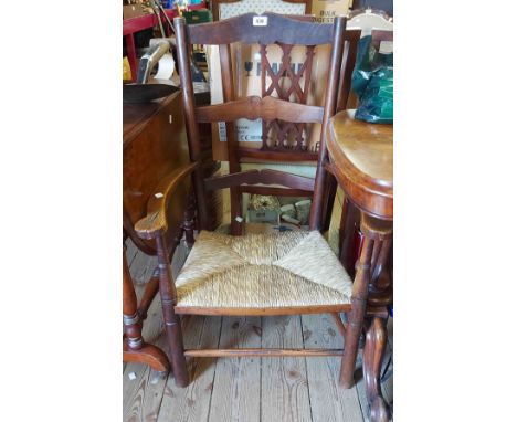 An antique elm framed ladder back low elbow chair with woven rush seat panel - joints loose