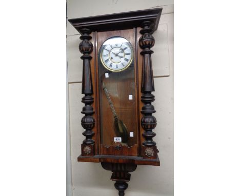 An early 20th Century Vienna regulator style wall clock with flanking part ebonised half columns, visible pendulum and eight 