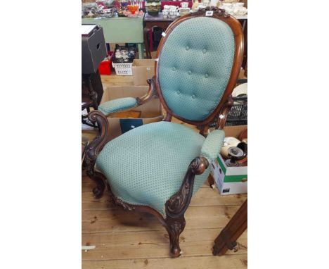 A Victorian carved mahogany part show frame spoon back elbow chair with button back upholstery, set on cabriole front legs wi