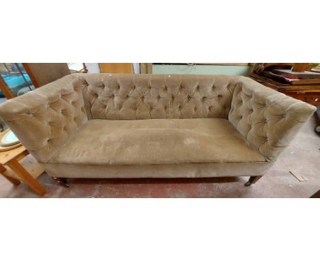 A 1.8m antique box frame settee with button back mushroom coloured velour upholstery, set on square tapered legs and casters