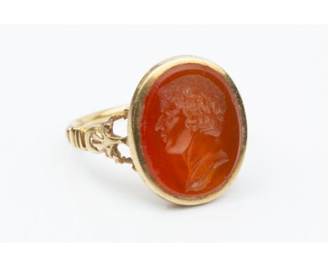 A 19TH CENTURY HARDSTONE INTAGLIO RING, the oval cornelian panel incised with a classical male portrait profile, in fluted cl