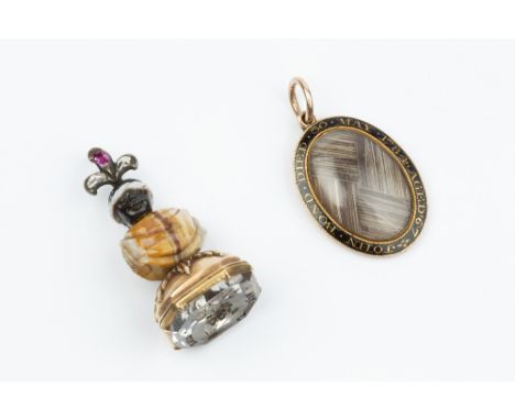 A 19TH CENTURY HARDSTONE SEAL FOB PENDANT, modelled as a blackamoor, with carved hardstone body and head, surmounted by a ros