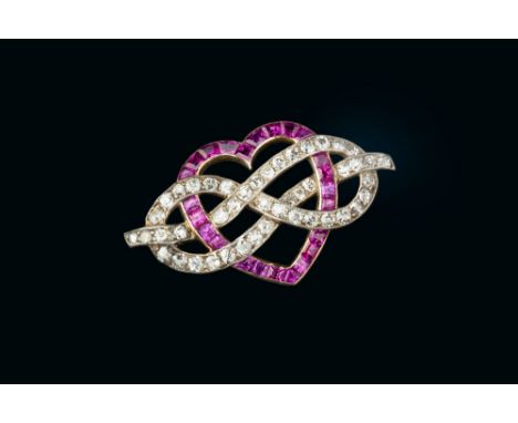 AN EARLY 20TH CENTURY RUBY AND DIAMOND PANEL BROOCH, the openwork panel modelled as a heart entwined with a lover's knot, set