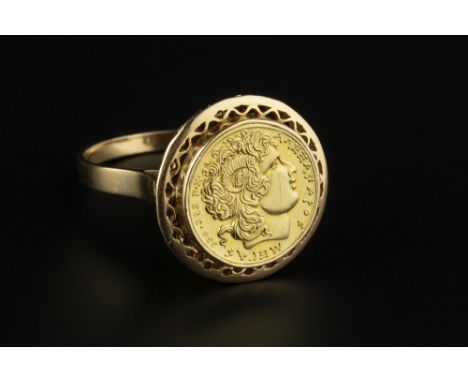 A YELLOW PRECIOUS METAL PANEL RING, depicting the portrait profile of Alexander the Great, with pierced border, stamped 'K18'