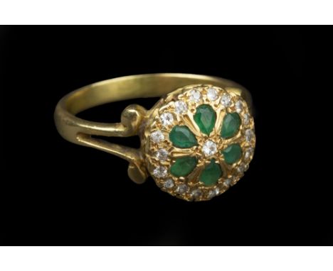 AN EMERALD AND DIAMOND PANEL RING, the circular panel with a cluster of pear-shaped emeralds and circular-cut diamonds in gra