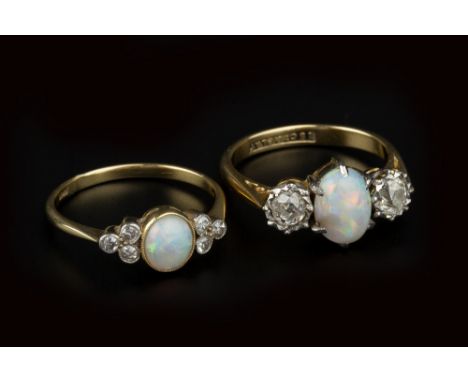 TWO OPAL AND DIAMOND DRESS RINGS, the first centred with an oval cabochon opal in claw setting, between two illusion set old-