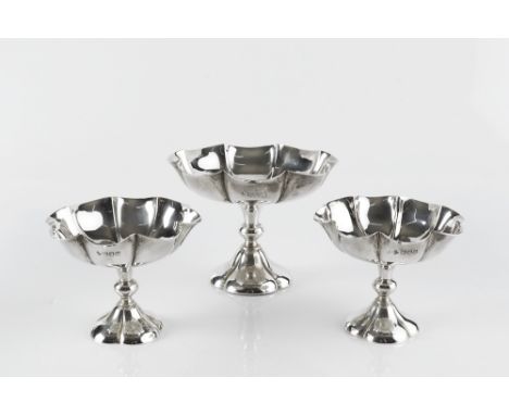 A SET OF THREE EDWARDIAN SILVER SWEETMEAT DISHES, comprising one large and two smaller, of lobed form, on knopped stems and l