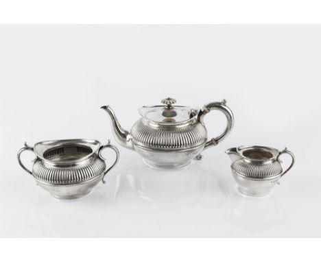 AN EDWARDIAN SILVER THREE PIECE BACHELOR'S TEA SERVICE, of compressed, half-lobed design, the teapot with ivory flower finial