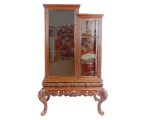 A 20th century Chinese carved hardwood display cabinet, the split level top with moulded and beaded cornice over two bevelled