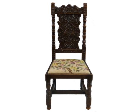 A Victorian oak hall chair, in the 17th century style, the top rail and panelled back carved with scrolls and leaves, within 