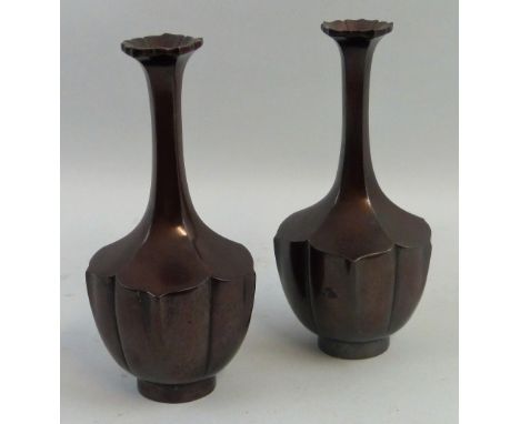 A pair of early 20th century Japanese bronze vases, each of bottle shaped form in the style of a flower head with flared rim,