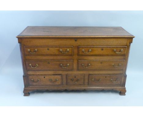 A George III Lancashire oak mule chest, with mahogany cross - banding, the hinged top over four dummy drawers with three real