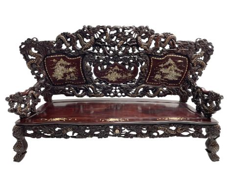 Early 20th century Chinese hardwood settee or hall-bench, the back pierced and heavily carved with dragons and trailing flowe