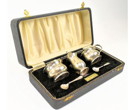 A hallmarked silver presentation cased cruet set comprising pepperette, blue glass lined table salt and lidded blue glass lin