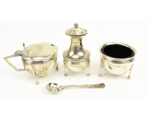 A George V three-piece silver hallmarked blue glass lined cruet set. The set to include a pepperette, a mustard pot and a tab