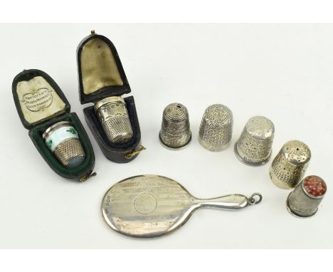 A collection of seven silver thimbles and a miniature mirror pendant. The lot to include a cased silver guilloche enamel thim