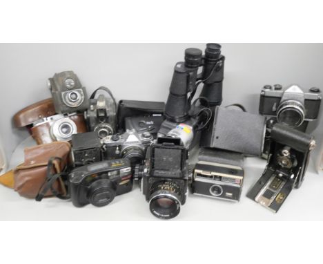 A collection of cameras including two Pentax, Mamiya 645 and Kodak Brownie, a Sony Handycam, binoculars and other accessories