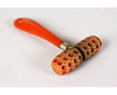 AN AMBER HANDLED FACE ROLLER, in a leather case.