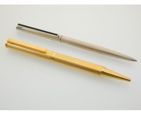 A Dunhill gold plated propelling pencil with ribbed body, together with a Dunhill white metal ballpoint pen with engine turne