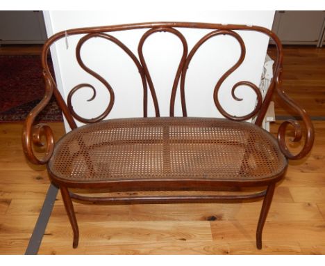 A late 19th century bentwood two seat sofa, with a cane seat and scroll open arms, W. 120cm.