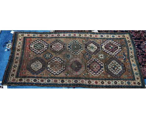 A GENDGE KAZAK RUG, CAUCASIANThe madder field with two columns of five hooked medallions, supporting flower heads and goats, 