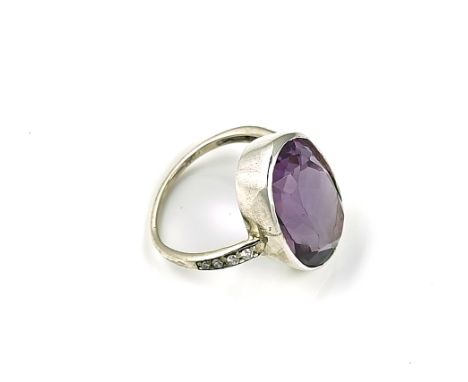 AN AMETHYST AND DIAMOND RINGCollet set with the oval cut amethyst between circular cut diamond set shoulders, detailed 750, r