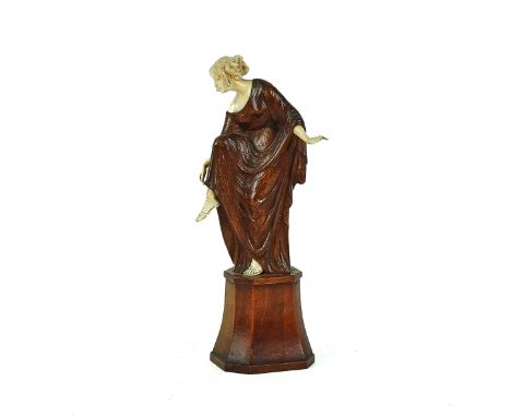 A CARVED IVORY AND WOOD SCULPTURE OF A FEMALE ADJUSTING HER SANDALCirca 1920, signed Bohm-HennesA carved wood and ivory sculp