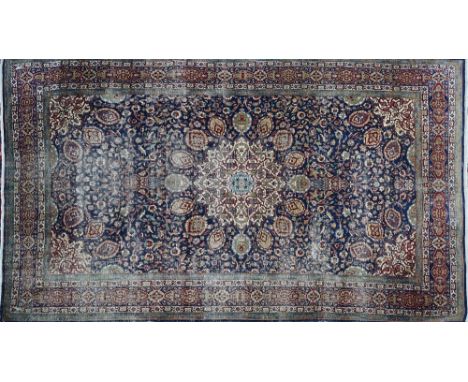 AN INDIAN CARPETThe indigo field with bold ivory faceted medallion, matching spandrels, all with abundantly floral sprays; a 