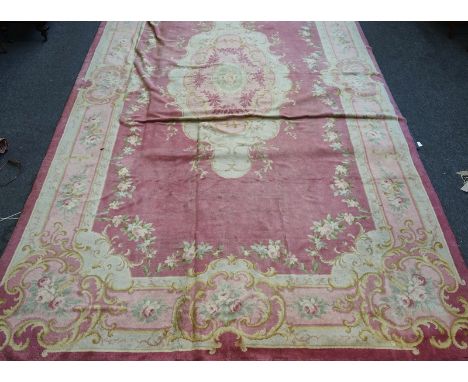 A DONEGAL CARPET, IRISHThe pink field with a large elongated cartouche, matching border with floral rose sprays, 614cm x 345c