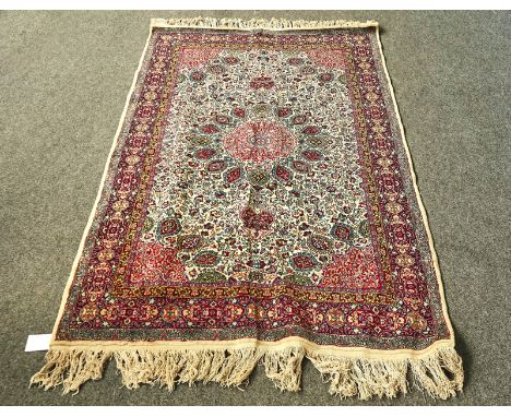 AN INDIAN RUGThe ivory field with a faceted medallion, madder spandrels, all over intricate floral sprays, an indigo cartouch