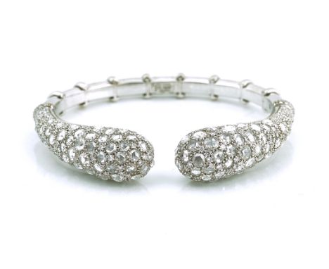 A DIAMOND SET HINGED BANGLE OF TORC DESIGN BY VIRGINIA CAPRISet in white gold, mounted with rose cut and with smaller circula