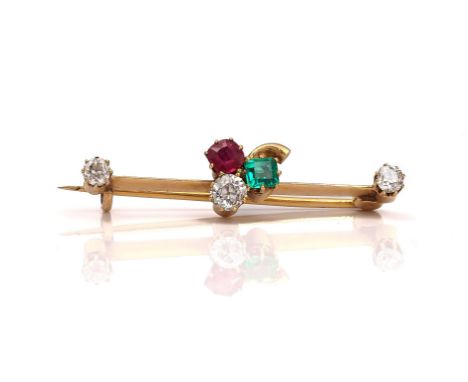 A GOLD, DIAMOND, EMERALD AND RUBY BAR BROOCHThe centre with a trefoil motif, mounted with a cushion shaped diamond, a cushion