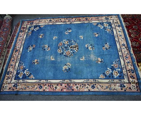 A CHINESE CARPETThe pale indigo field with a floral roundel, matching spandrels, single floral sprays and butterflies, a pink