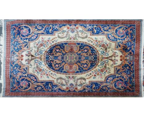 A CHINESE CARPET OF EUROPEAN DESIGNThe ivory field with a bold indigo roundel, matching surround with bold scrolling 406cm lo