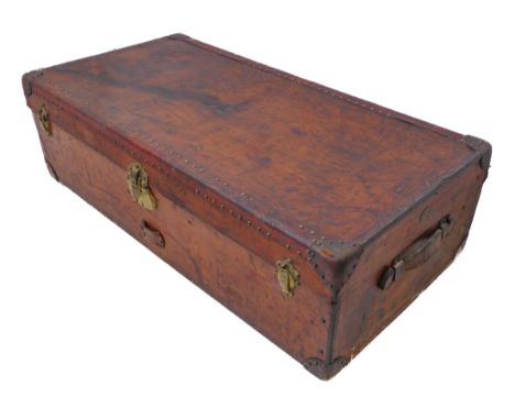 A fine patinated brown leather travelling trunk: two side carrying handles and one end with applied oval Parisian brass maker